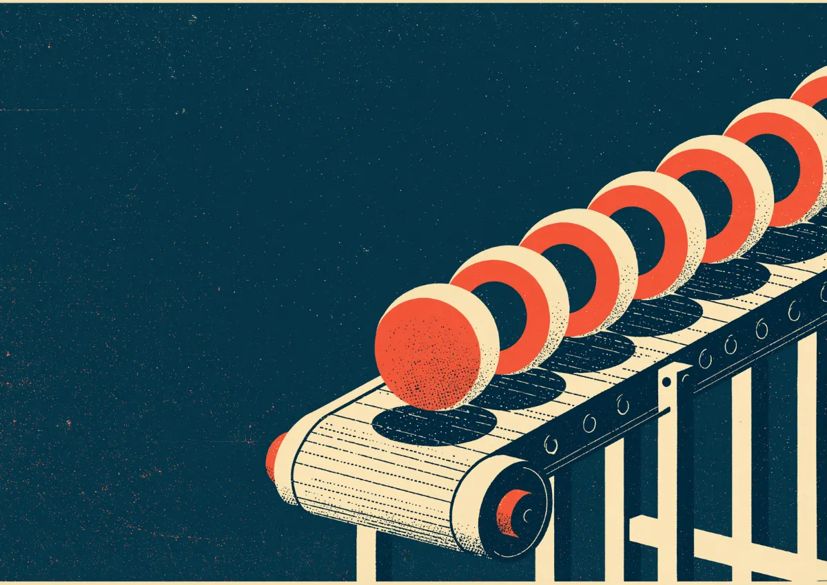 A conveyor belt carrying a row of identical red domed items